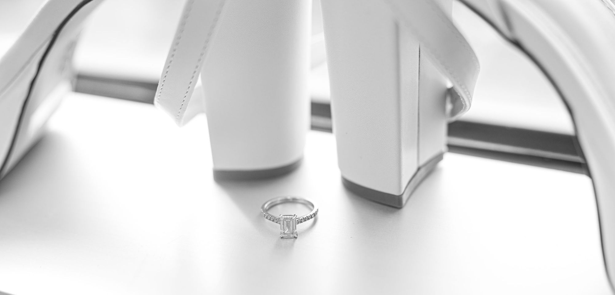 Engagement ring resting between white bridal heels
